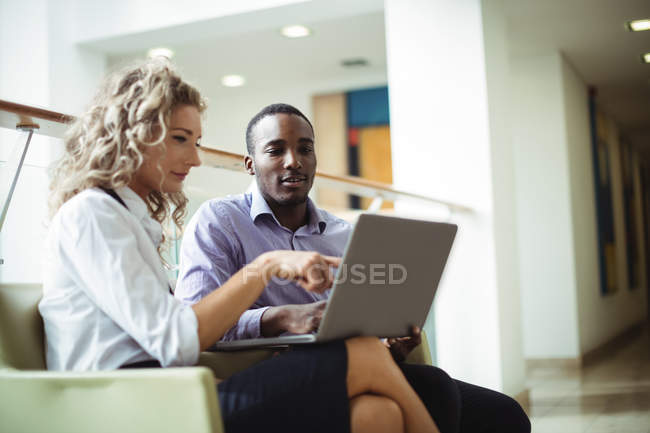 Führungskräfte diskutieren über Laptop auf Büroflur — Stockfoto