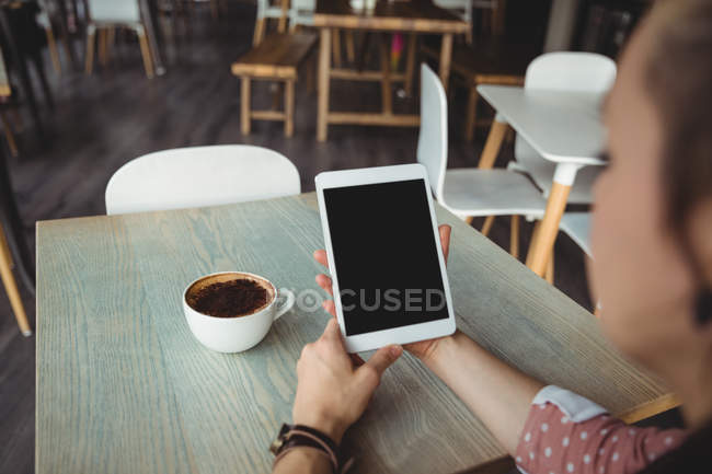 Donna che utilizza tablet digitale mentre ha una tazza di caffè nel caffè — Foto stock