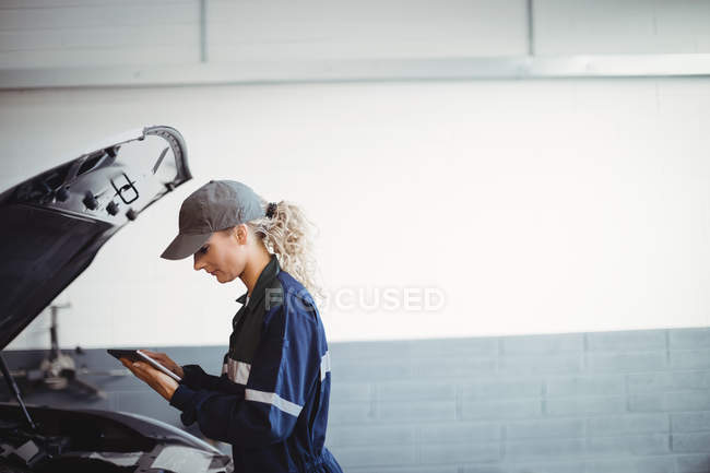 Female mechanic using digital tablet in repair garage — Stock Photo
