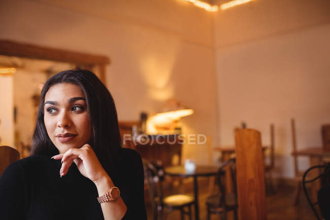 Задумчивая женщина сидит в кофейне — стоковое фото