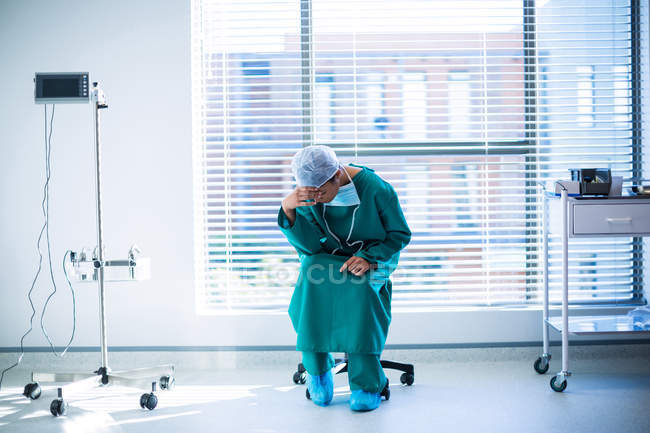 Напружений жіночий хірург сидить в коридорі лікарні — стокове фото