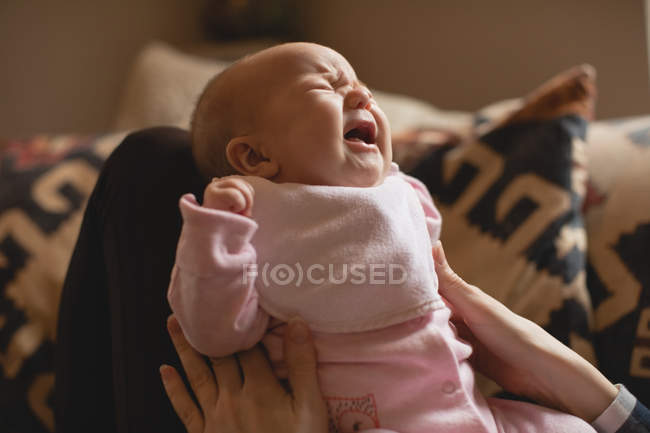 Close-up da mãe consolando choro bebê na sala de estar em casa — Fotografia de Stock
