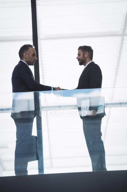 Businessman greeting a colleague in corridor of an office building — Stock Photo