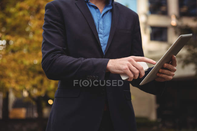Mittelteil des Geschäftsmannes hält Handy und nutzt digitales Tablet auf der Straße — Stockfoto