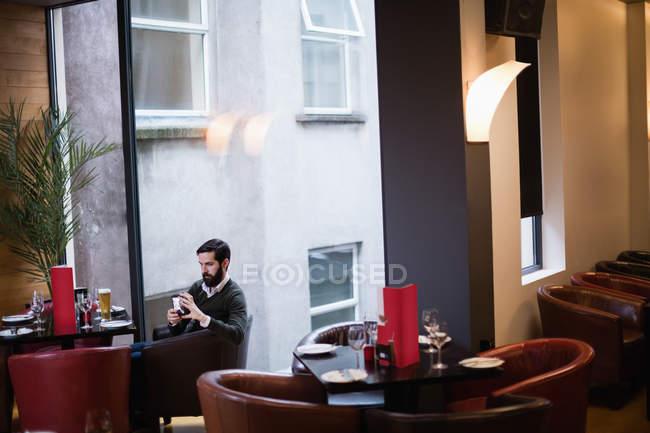 Mann benutzte Handy während er in Bar saß — Stockfoto