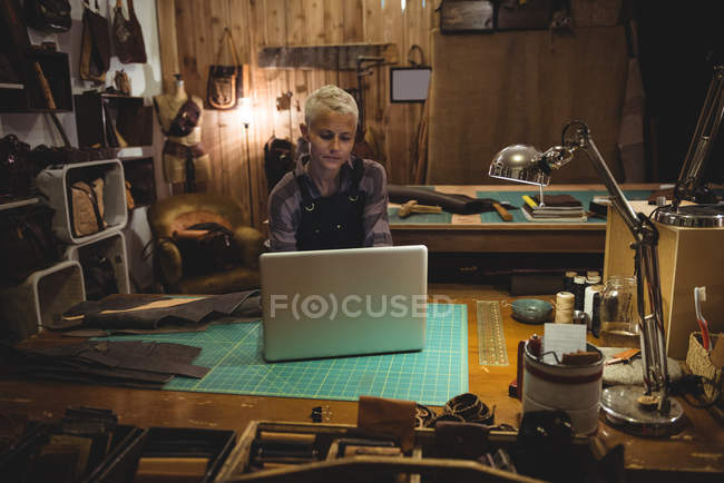 Mature craftswoman using laptop in workshop — Stock Photo
