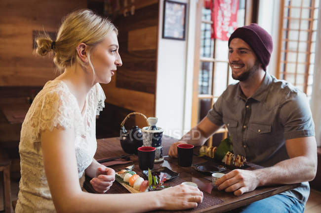 Casal interagindo enquanto tendo sushi no restaurante — Fotografia de Stock
