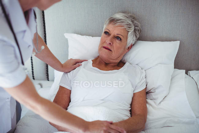 Doctora interactuando con paciente mayor en casa - foto de stock
