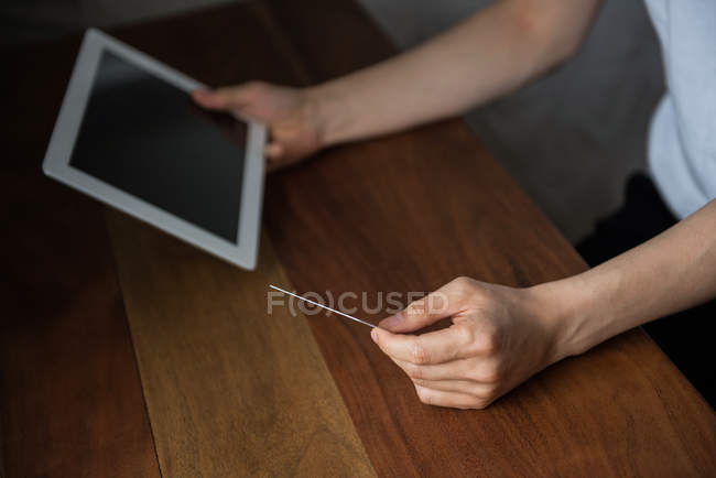 Sección media del hombre haciendo compras en línea en tableta digital en casa - foto de stock