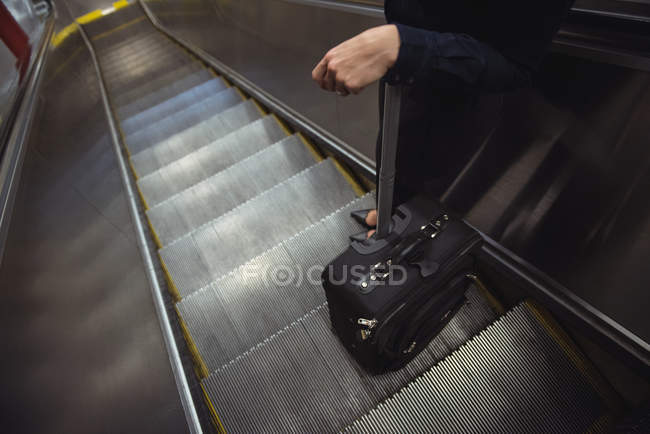 Section basse de femme d'affaires avec des bagages debout sur l'escalier roulant — Photo de stock