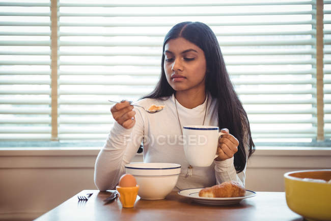 Frau frühstückt zu Hause im Wohnzimmer — Stockfoto