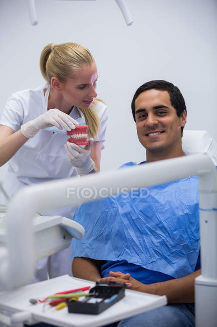 Стоматолог, що показує набір модельних зубів пацієнту в клініці — стокове фото