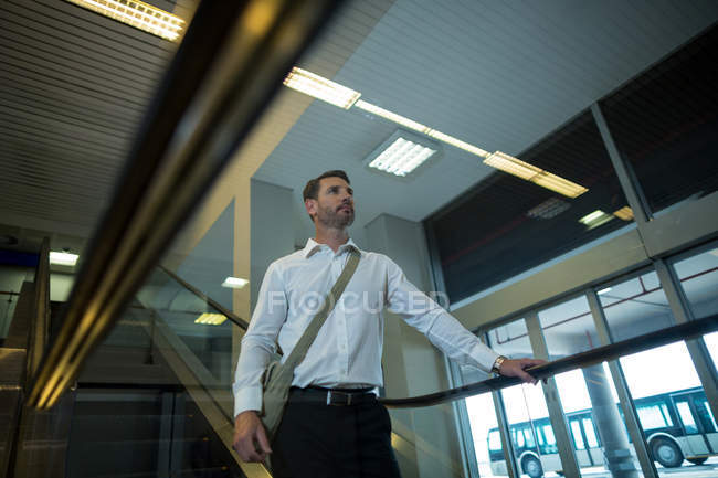 Hombre guapo en escaleras mecánicas en el aeropuerto - foto de stock