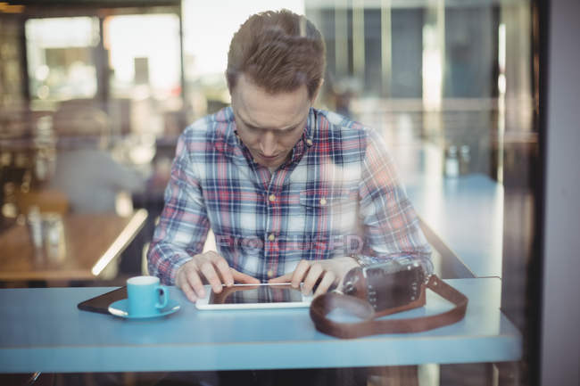 Young man using digital tablet in cafeteria — Stock Photo