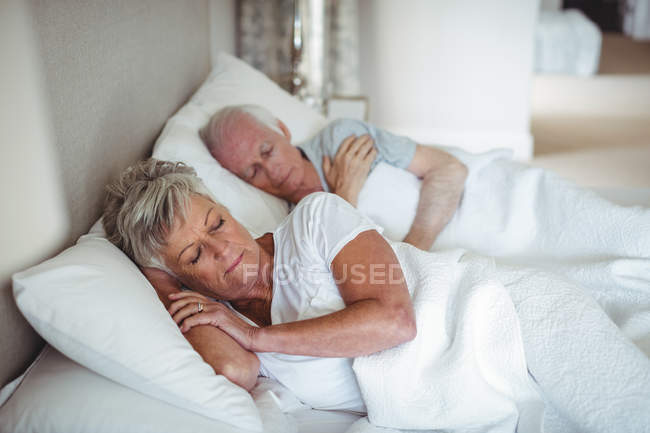 Senior couple sleeping on bed in bedroom — Stock Photo