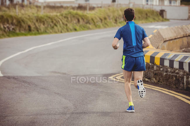 Vista posteriore dell'uomo che fa jogging sulla strada aperta — Foto stock