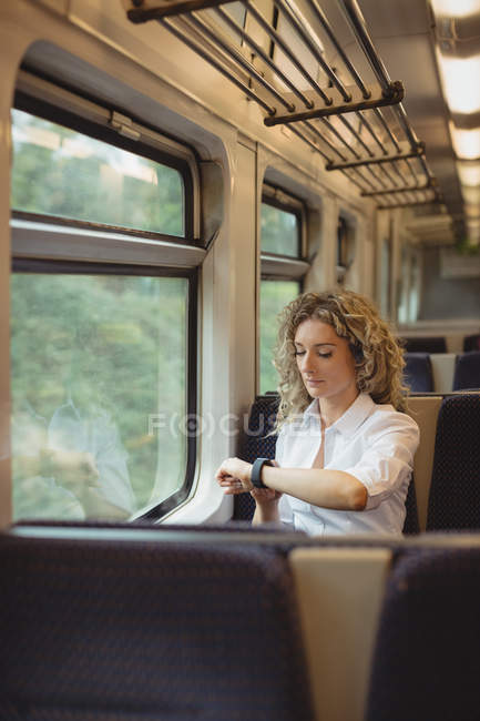 Femme d'affaires réfléchie vérifier l'heure sur montre-bracelet tout en voyageant — Photo de stock