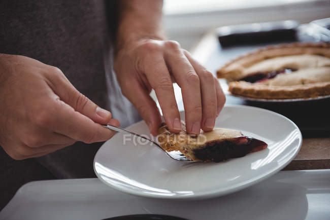Середній розділ людини, що видаляє шматочок чорничного пирога на кухні — стокове фото