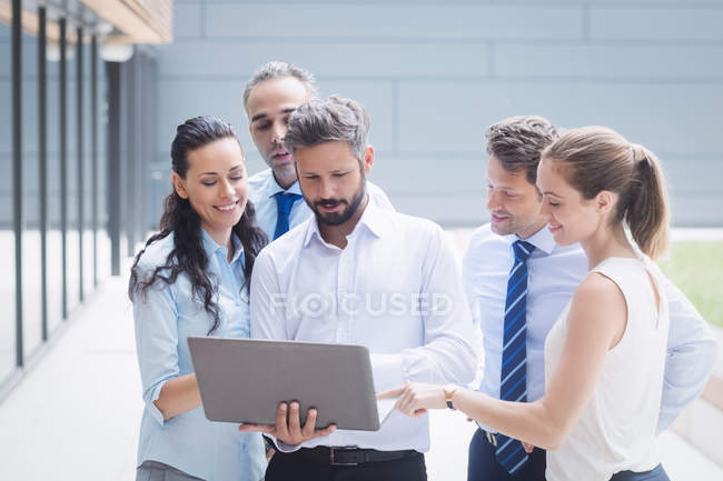 Groupe de gens d'affaires discutant sur ordinateur portable à l'extérieur de l'immeuble de bureaux — Photo de stock