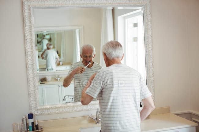 Uomo anziano lavarsi i denti in bagno — Foto stock