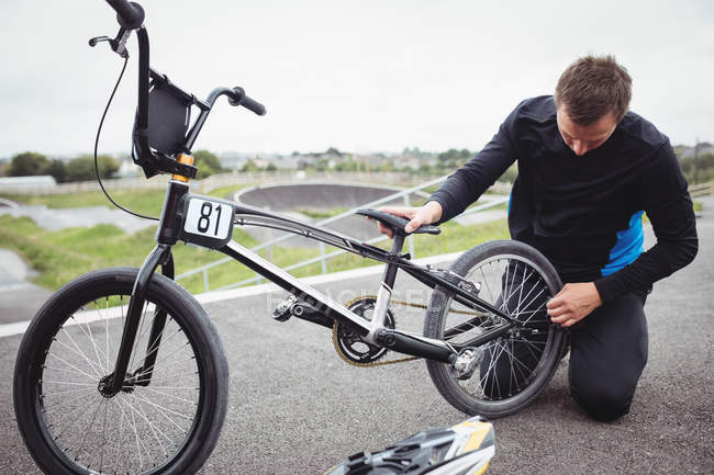 Cycliste réparant un vélo BMX dans un skatepark — Photo de stock