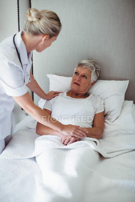 Médica interagindo com paciente sênior em casa — Fotografia de Stock
