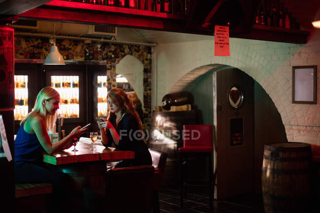 Красиві жінки використовують мобільний телефон в барі — стокове фото
