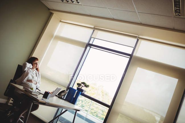 Schwangere Geschäftsfrau hält sich im Büro auf Stuhl zurück — Stockfoto
