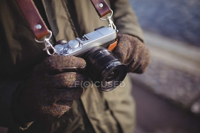 Mid-section of man holding camera outdoors — Stock Photo