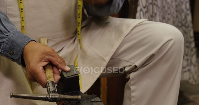Sapateiro martelando em um sapato na oficina — Fotografia de Stock