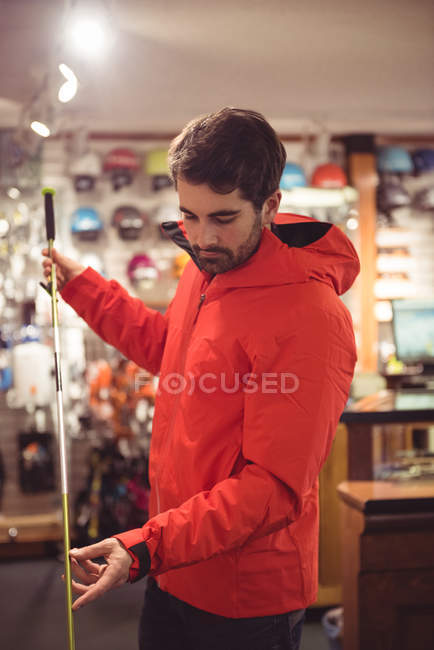 Bonito homem selecionando pólo de esqui em uma loja — Fotografia de Stock