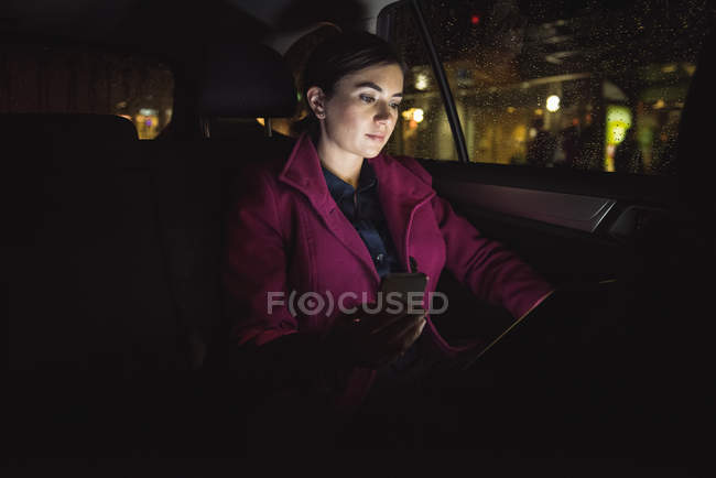 Hermosa mujer de negocios utilizando tableta digital y teléfono en el coche - foto de stock