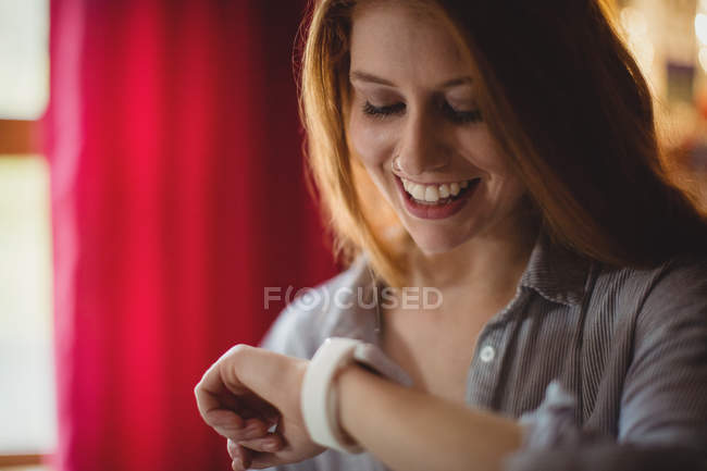 Усміхнена жінка перевіряє свій смарт-годинник вдома — стокове фото