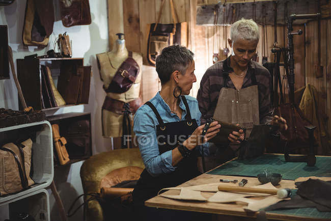 Kunsthandwerker diskutieren in Werkstatt über Ledertasche — Stockfoto