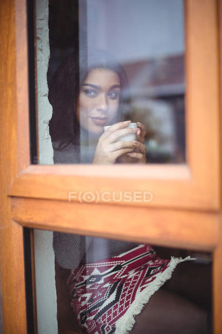 Femme réfléchie prenant une tasse de café dans un café — Photo de stock