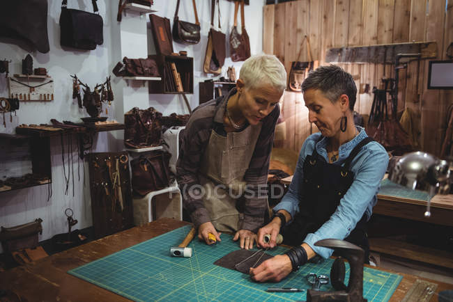 Artesãos discutindo sobre um pedaço de couro na oficina — Fotografia de Stock