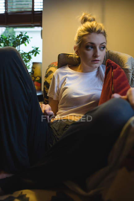 Woman sitting on couch in living room at home — Stock Photo