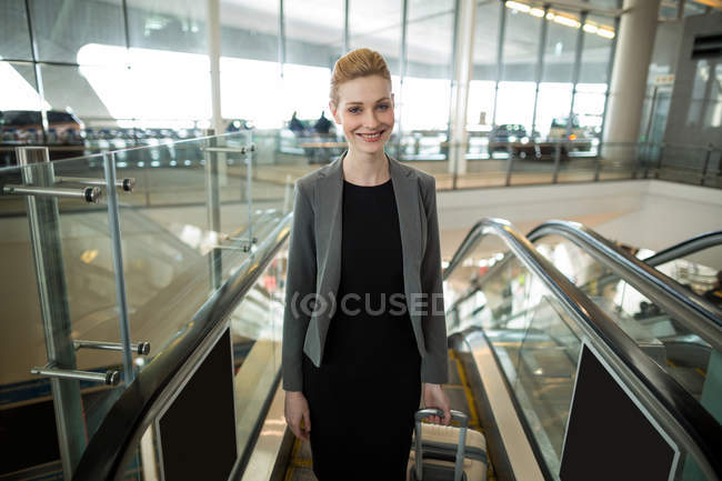 Donna d'affari in piedi vicino alla scala mobile con bagagli in aeroporto — Foto stock