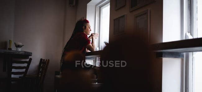 Femme réfléchie prenant un café dans un café — Photo de stock