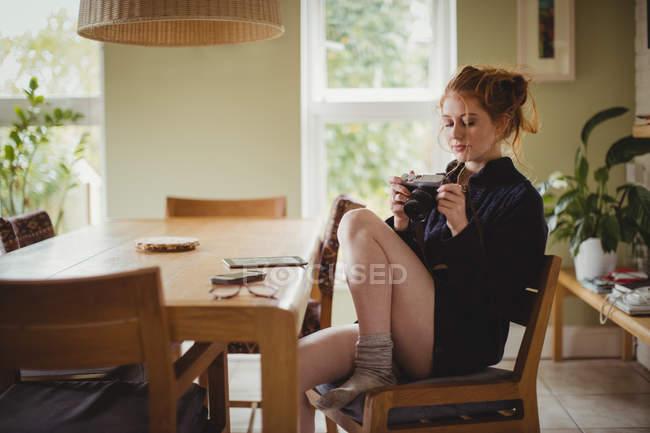 Mulher bonita olhando para fotos na câmera digital em casa — Fotografia de Stock