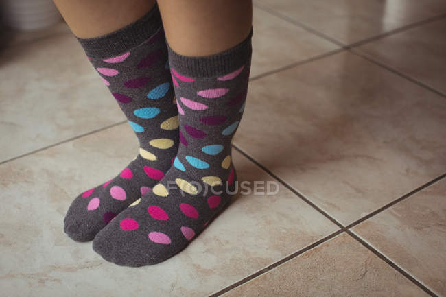 Pés femininos vestindo bolinhas multicoloridas meias em casa — Fotografia de Stock