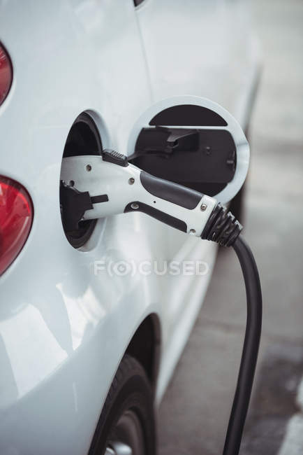 Close-up of car being charged with electric car charger at charging station — Stock Photo