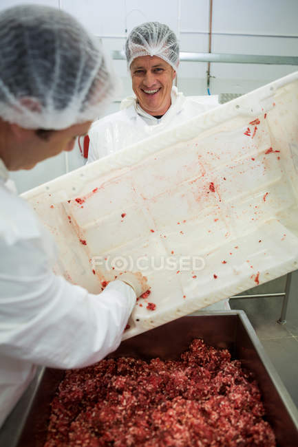 Macellai svuotano vassoio con carne macinata in fabbrica di carne — Foto stock