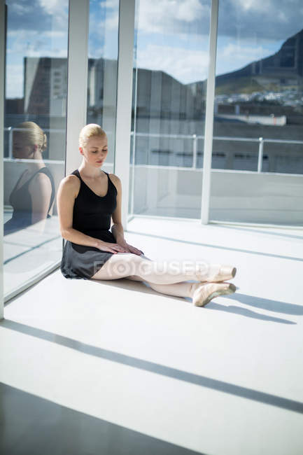 Балерина сидит у стеклянного окна в студии — стоковое фото