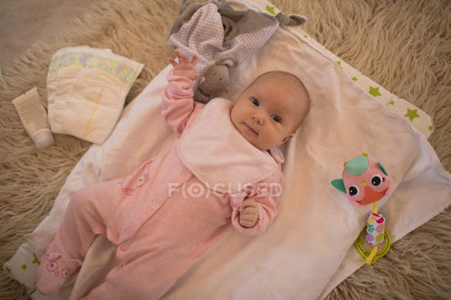 Mignon bébé couché sur le tapis dans le salon à la maison avec des jouets — Photo de stock