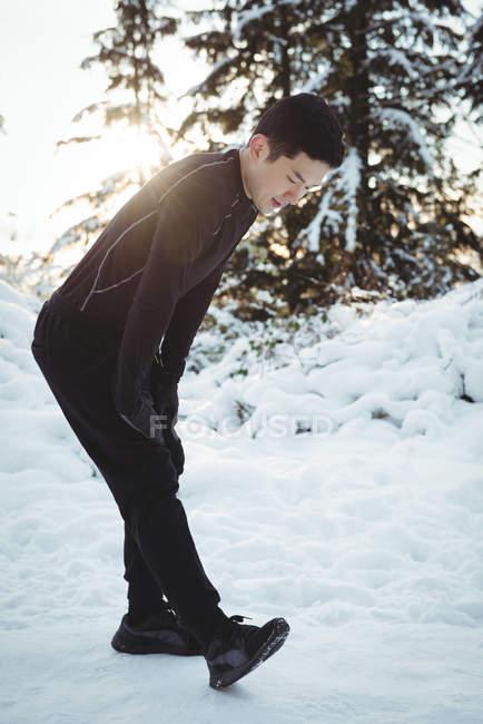 Чоловік розтягує ноги в лісі взимку — стокове фото