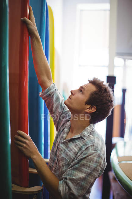 Homem olhando para pranchas coloridas na loja — Fotografia de Stock