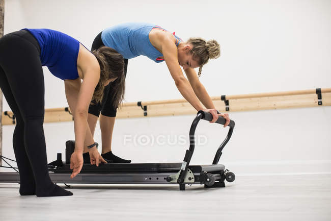 Trainerin unterstützt Frau bei Dehnübungen am Reformer im Fitnessstudio — Stockfoto