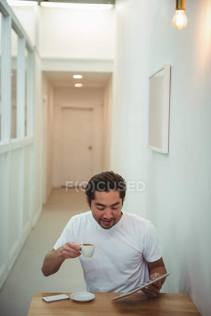 Homme utilisant une tablette numérique tout en prenant un café dans un café — Photo de stock