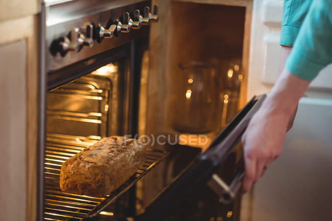 Жінка випікає хліб в духовці вдома — стокове фото